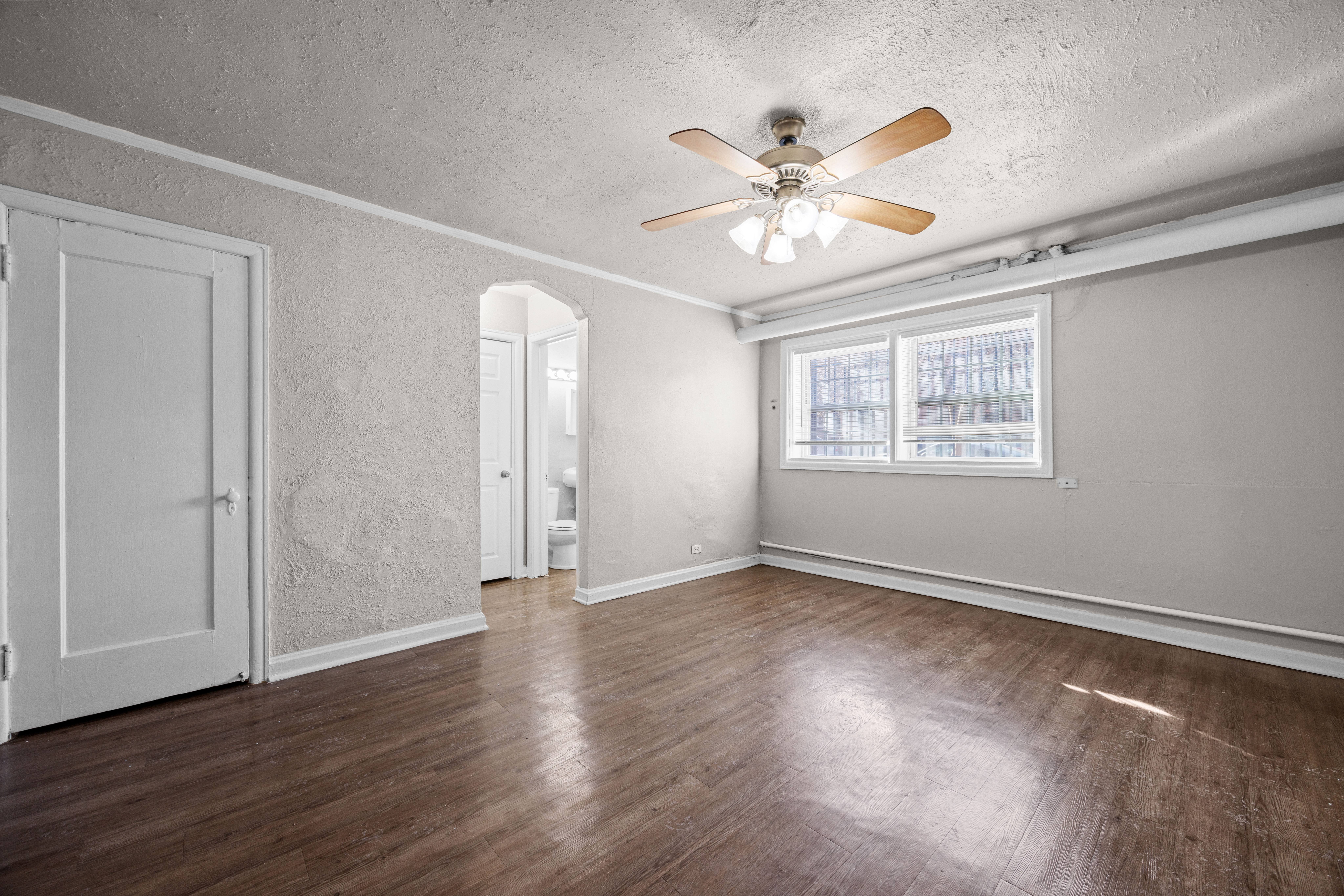 A room with a ceiling fan and wooden floors.